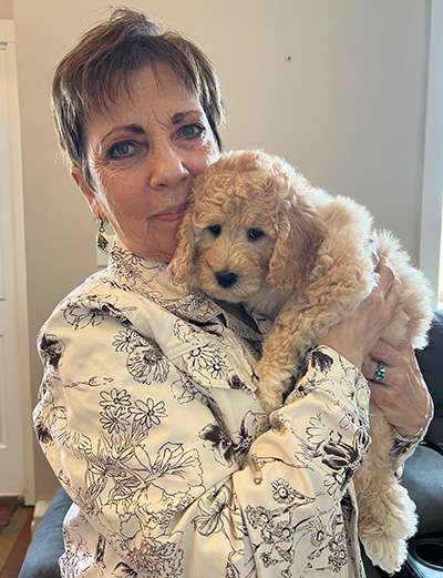 A woman holding a Goldendoodle puppy.