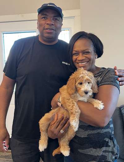 A family of two holding their new Goldendoodle puppy from Lakeshore Doodles.